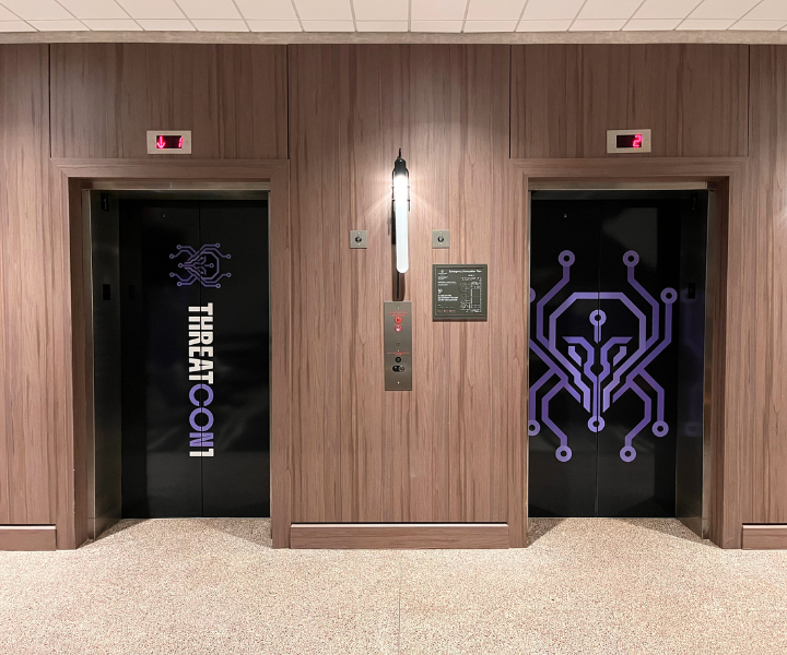Hotel elevator doors transformed with THREATCON1 branded graphics as part of a cohesive conference environment